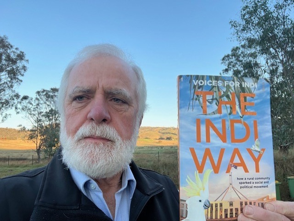 Denis Ginnivan holding Voices of Indi book
